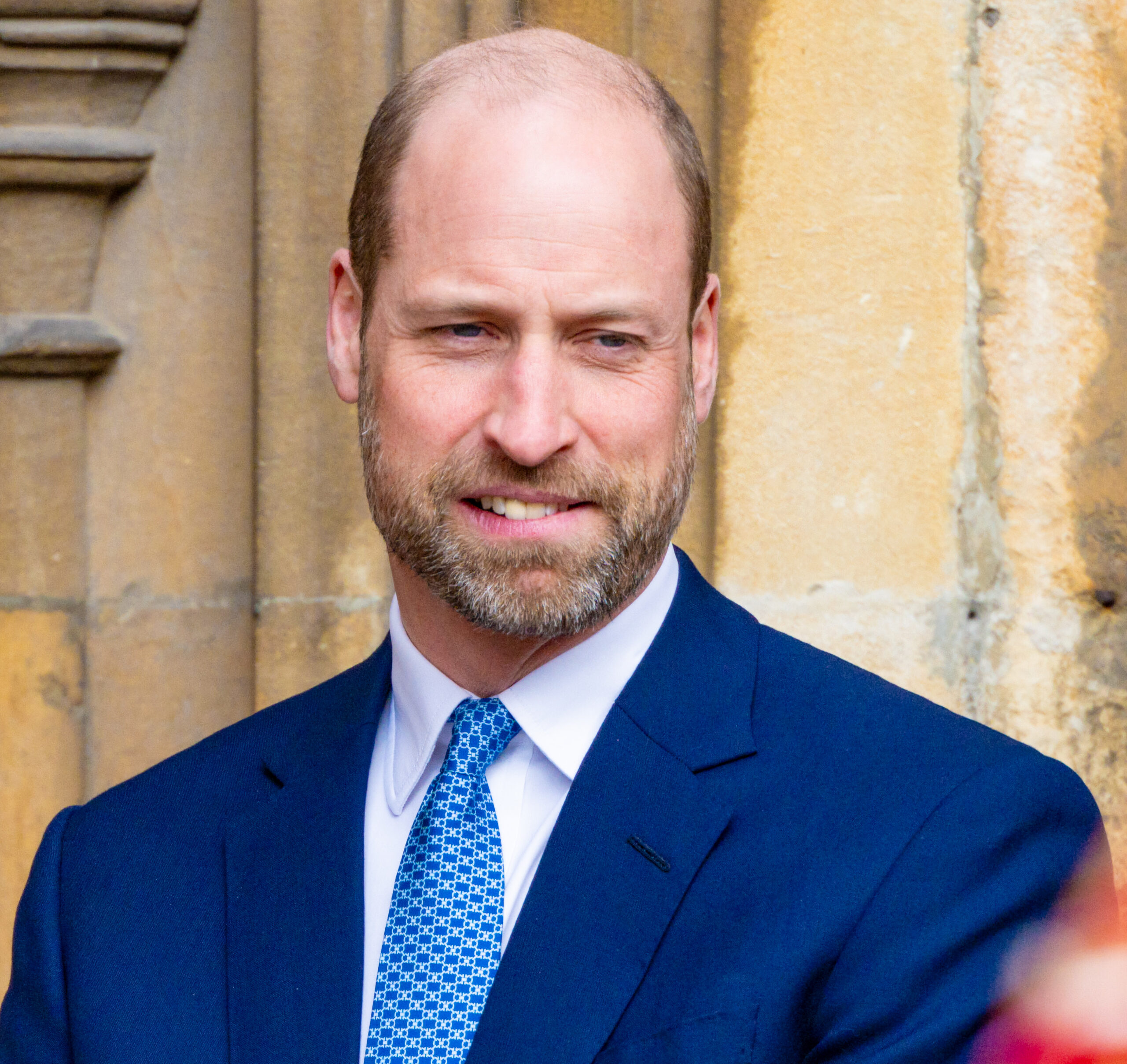 Prince William biting his lip wearing a navy suit