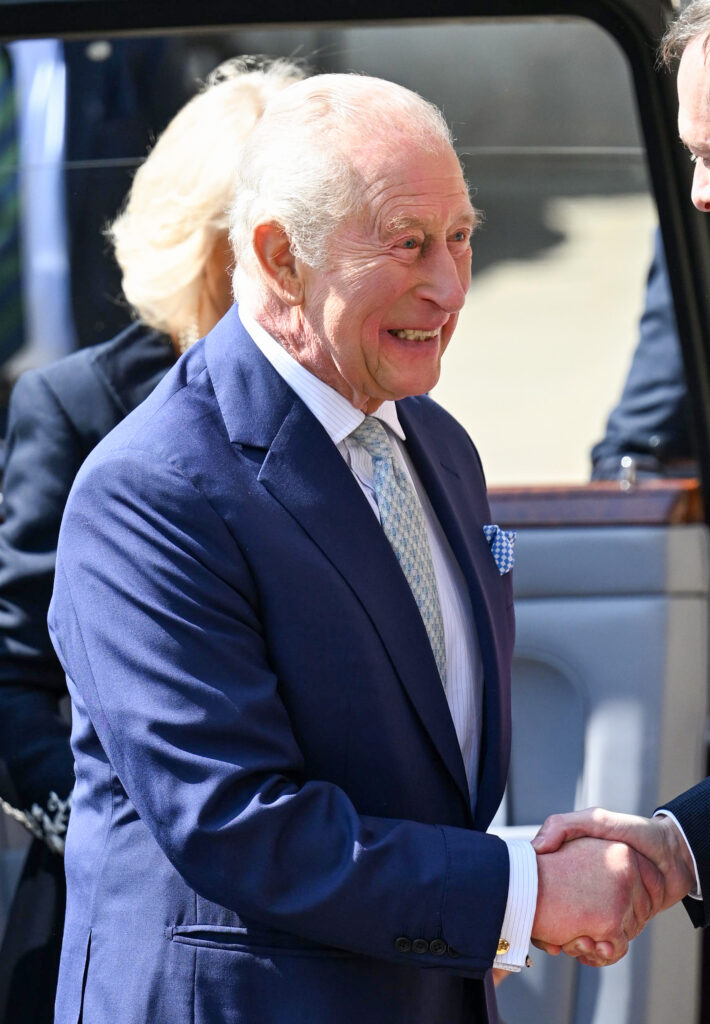 King Charles grinning as he shakes someones hand