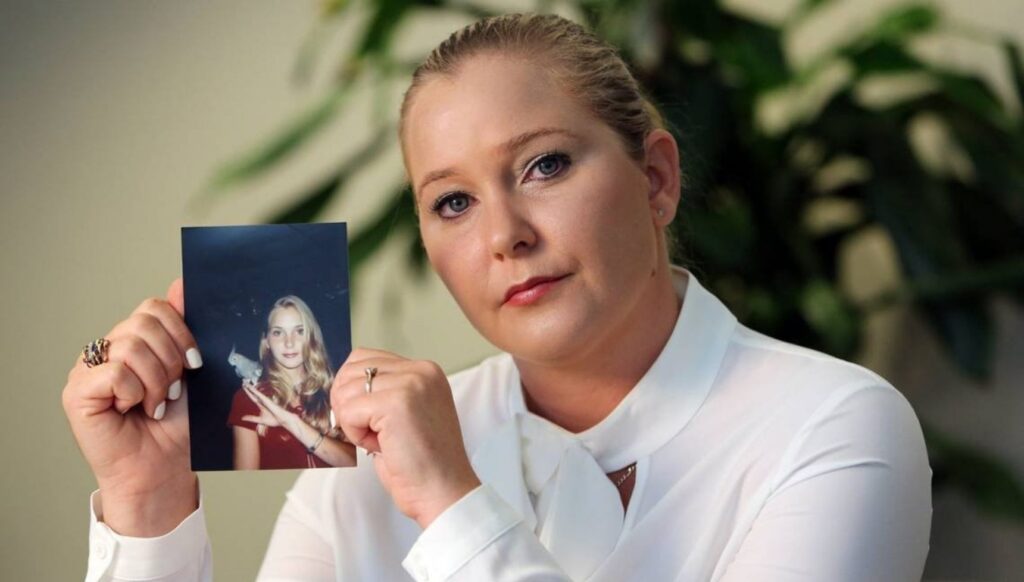 Virginia Giuffre holding up a photo of her younger self
