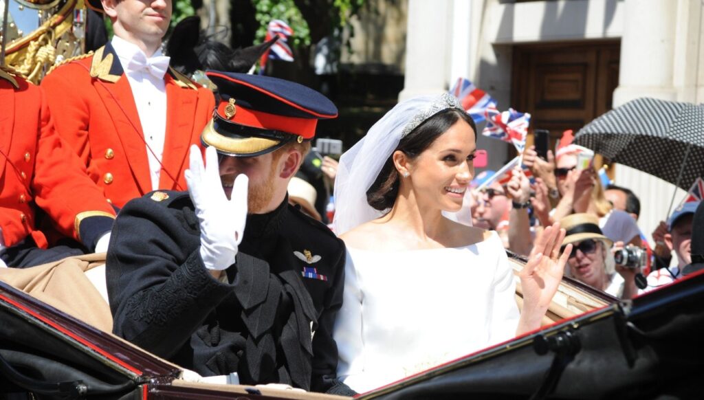 Prince Harry and Meghan Markle smiling and waving on their wedding day