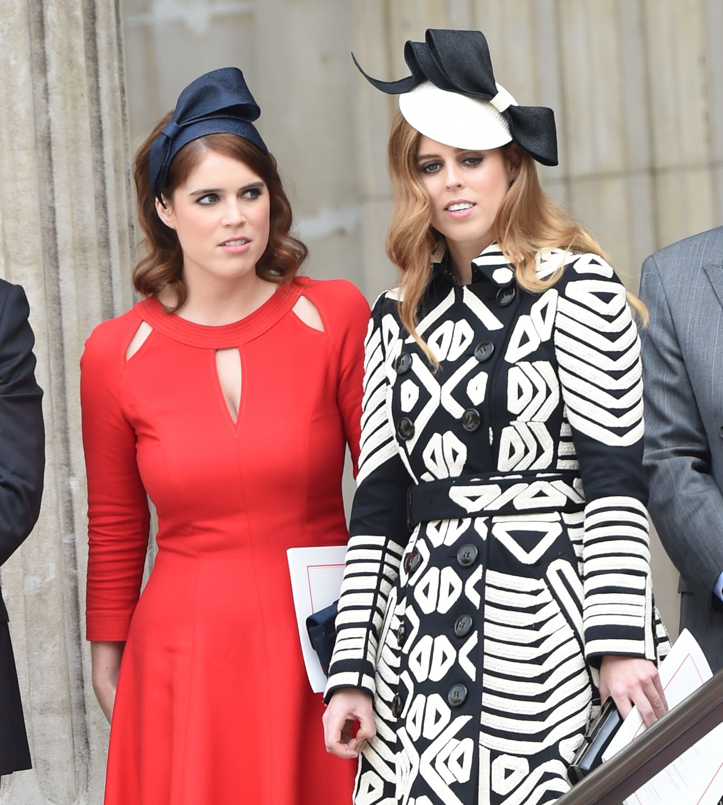 Princess Eugenie frowning beside Princess Beatrice who has a confused smile on her face