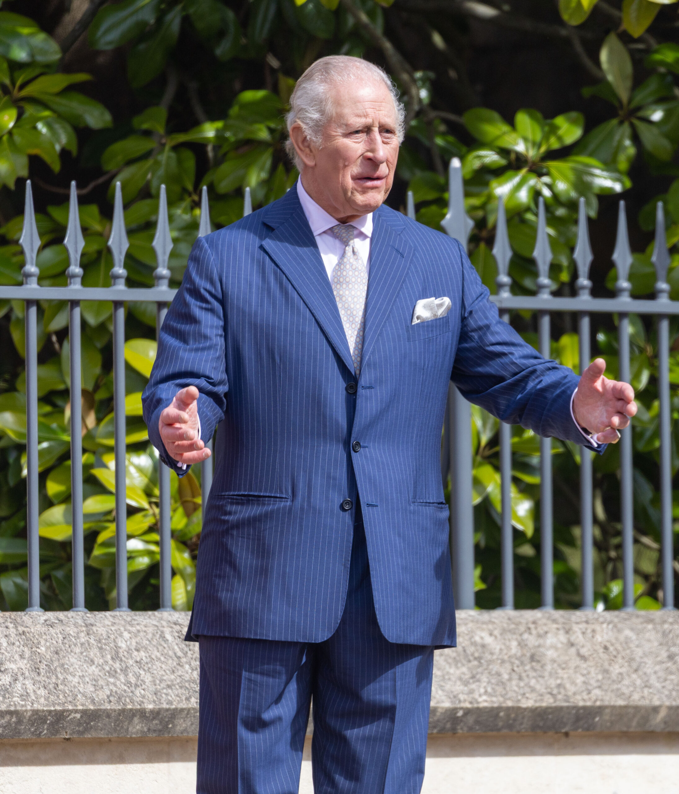 King Charles putting his arms out in blue suit